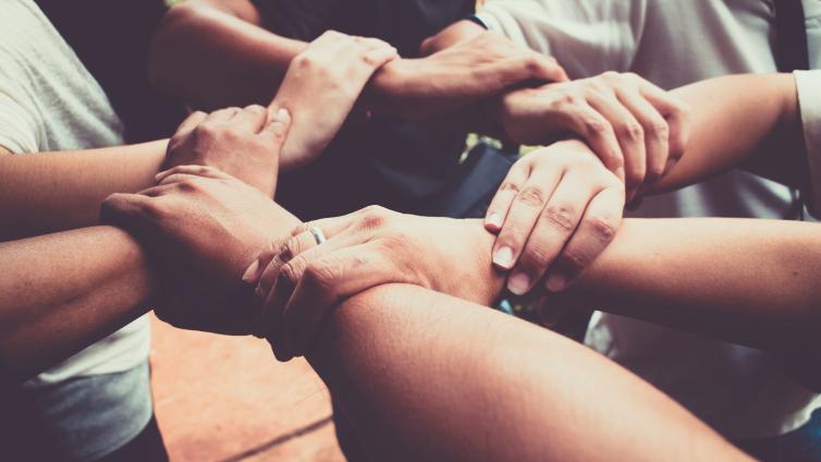 Arms and hands grasping each other in support in a circular formation